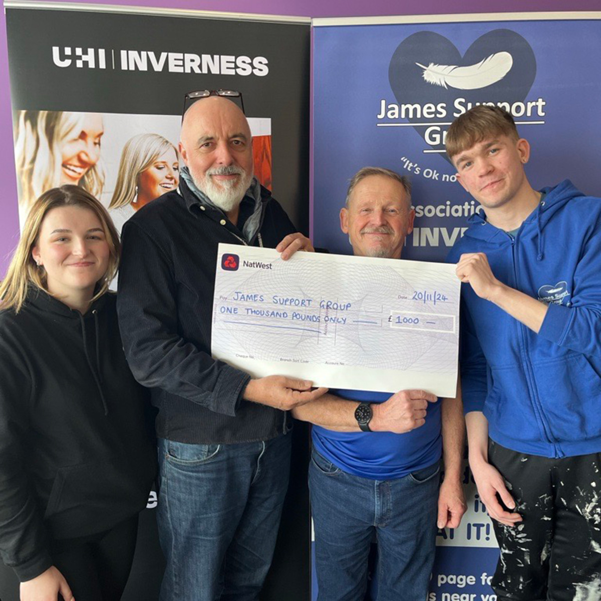 Four people holding a giant cheque