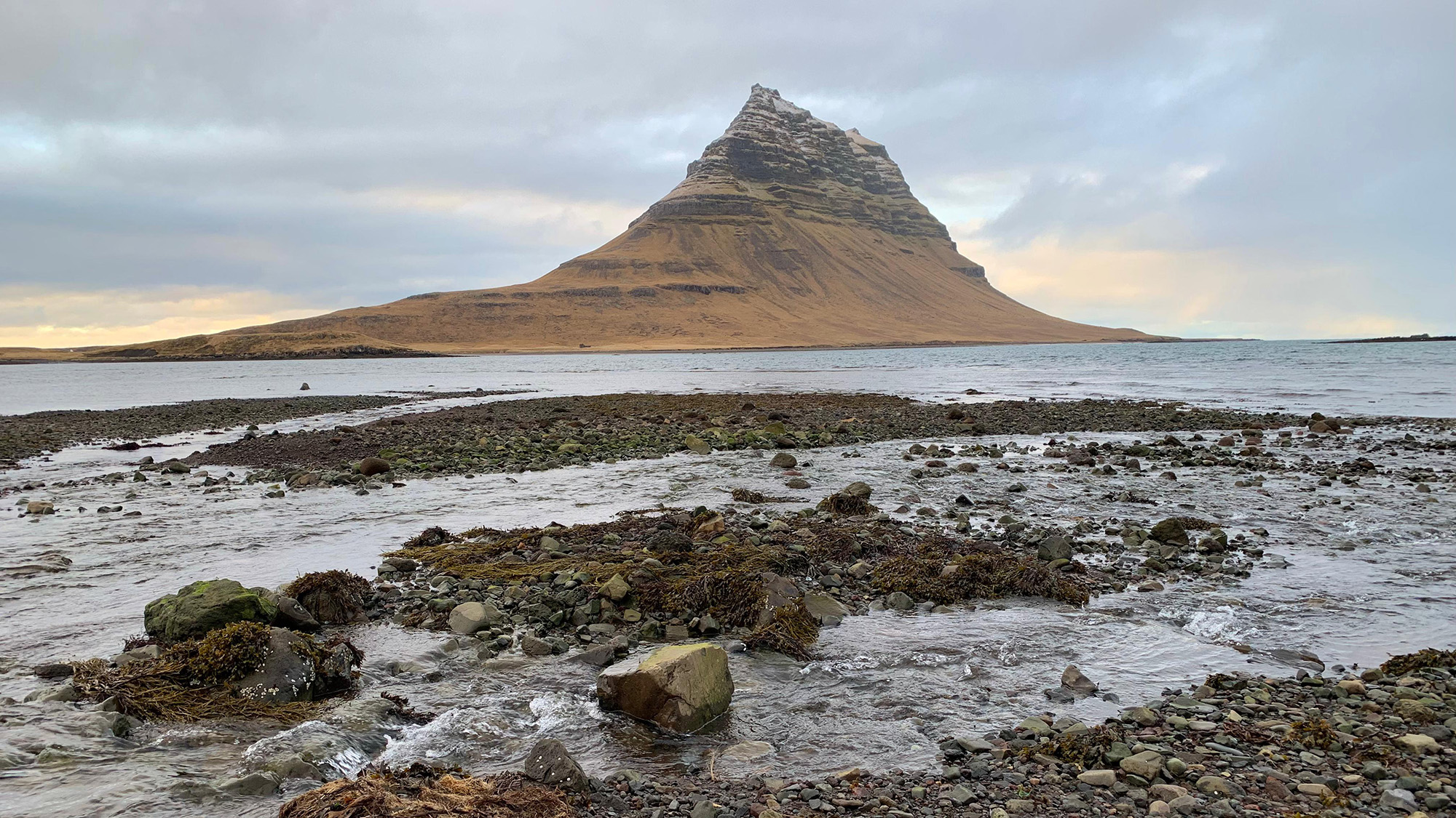 Volcano shaped hill with a rocky shoreline in the foreground