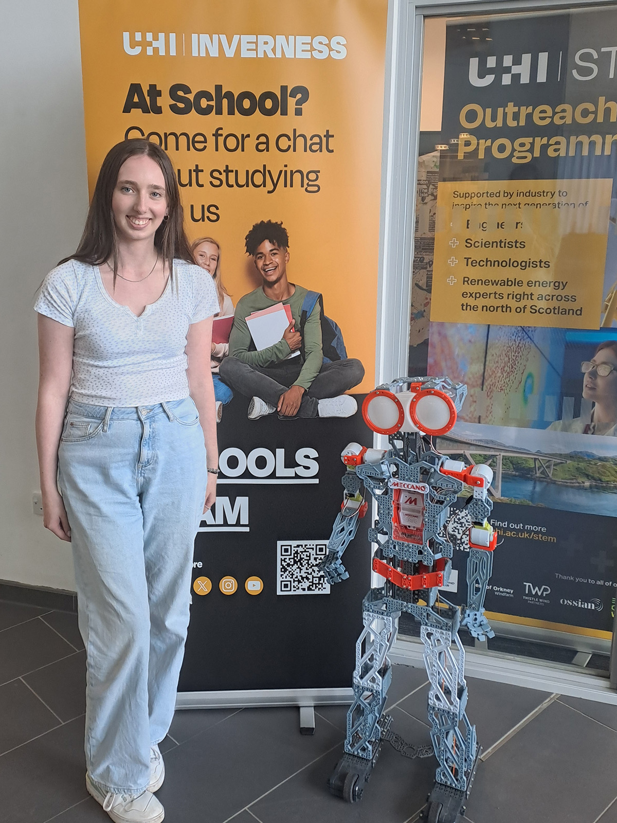 Student standing with robot