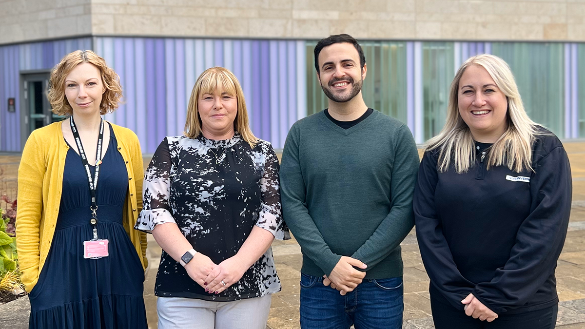 A man and three women standing in a row outside UHI Inverness building