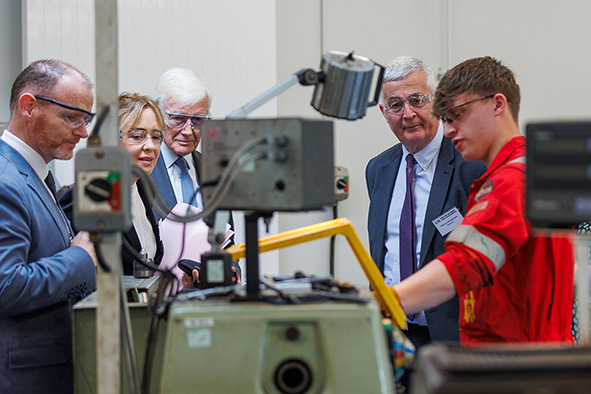 Four people watch on as a student demonstrates equipment.