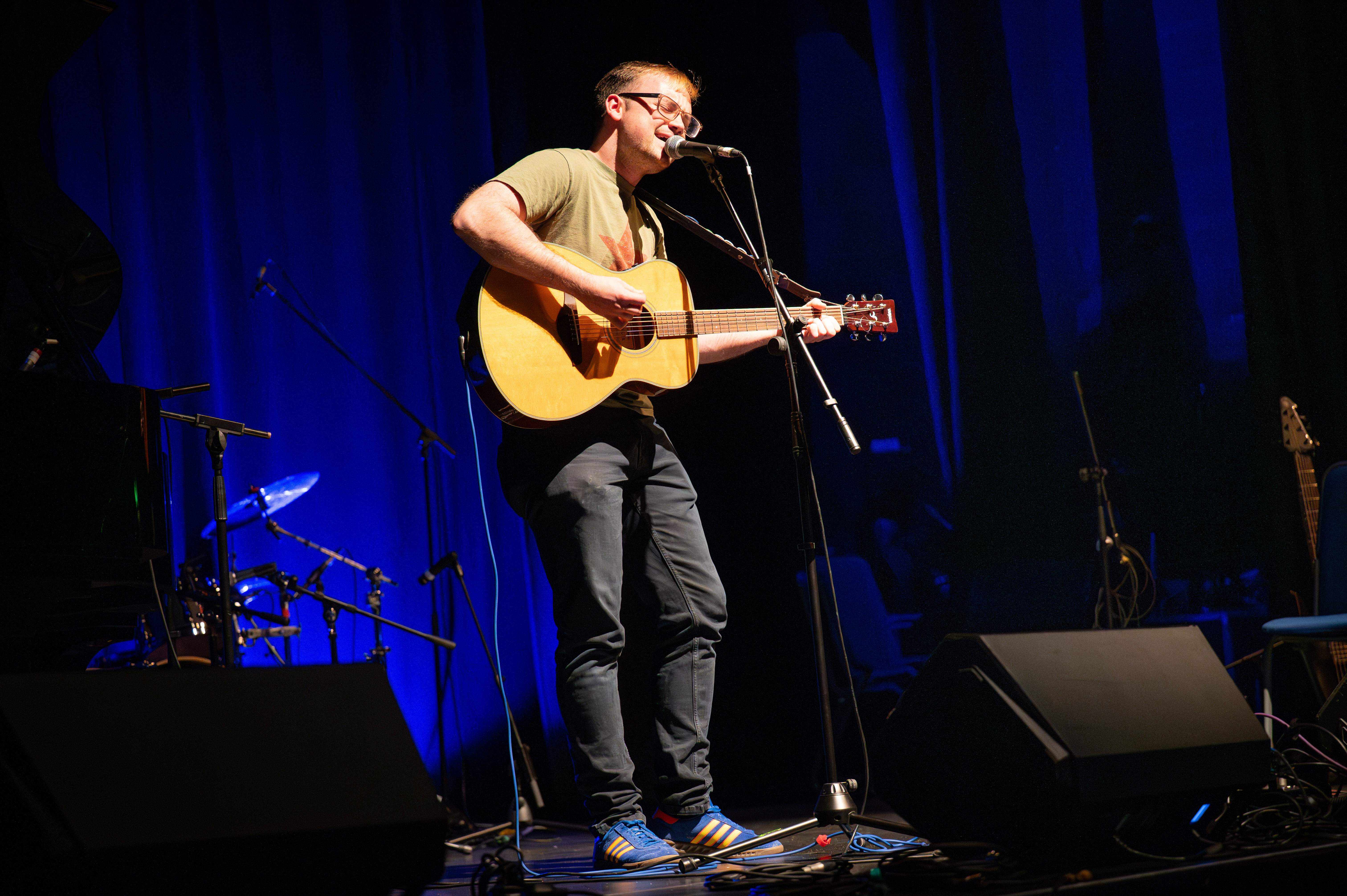 Student on stage with guitar singing