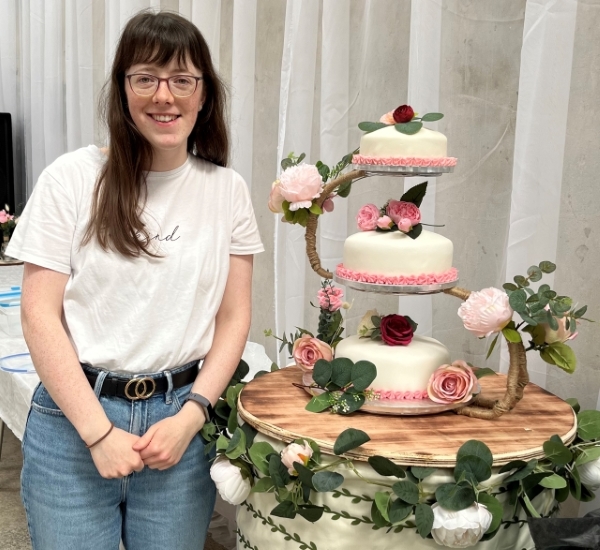 Alice Mainland standing in front of a three tiered cake
