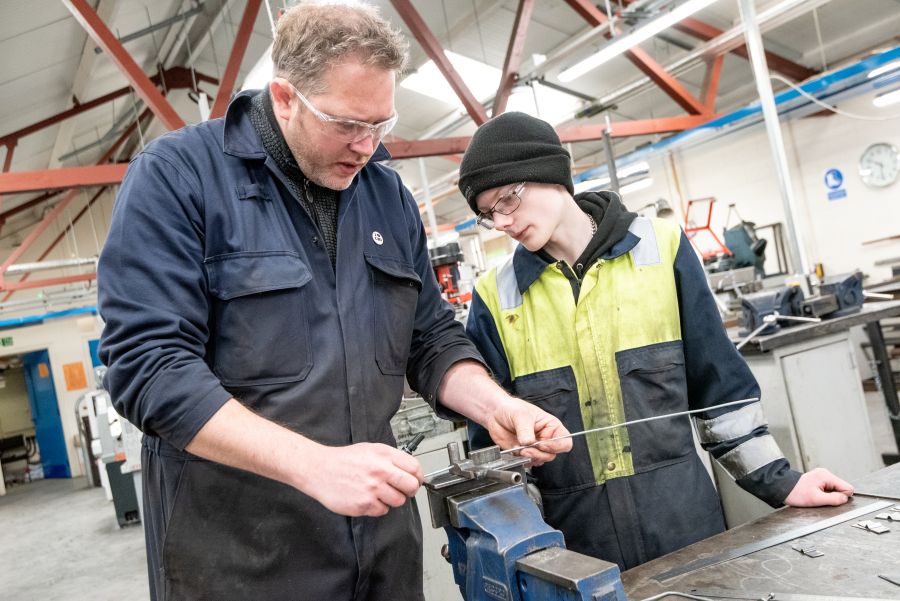 Person demonstrating manufacturing process to another person Person demonstrating manufacturing process to another person