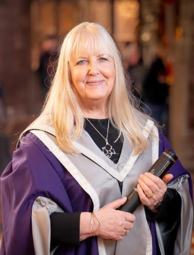 Sheila Fleet OBE, in gown holding certificate