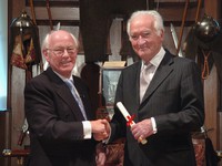 Two people shaking hands posing for the camera wearing formal business attire Two people shaking hands posing for the camera wearing formal business attire