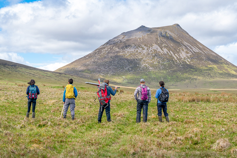 Five researchers standing in a field with research equipment