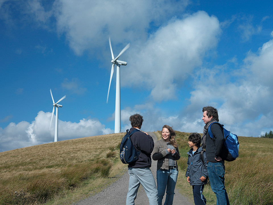 Four people standing in front of a wind turbine