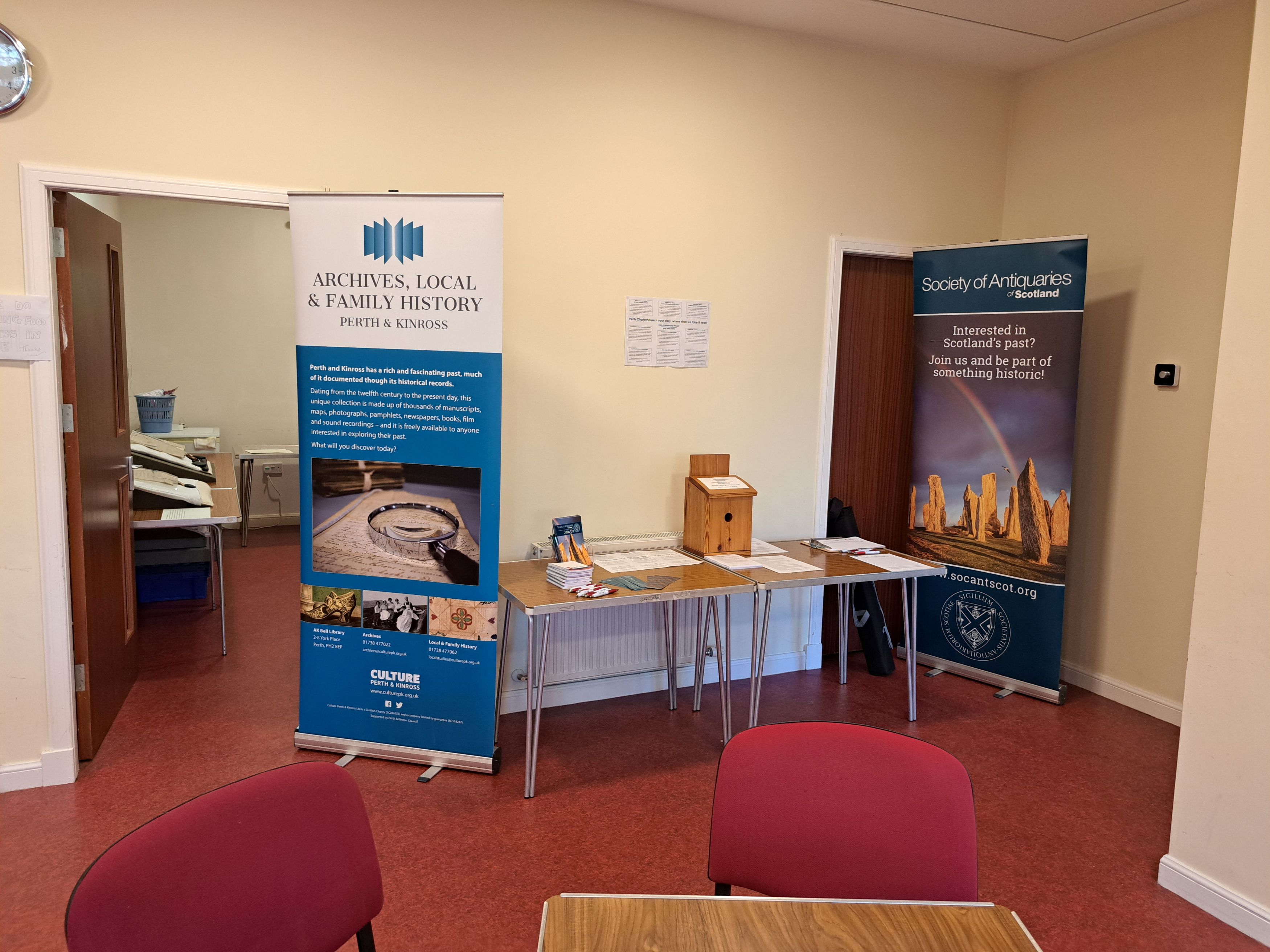A table set up with papers and pens. Next to it two banners promote Society of Antiquaries and Archives, Local and Family History