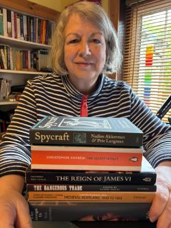 Woman depicted with a pile of books in front of her