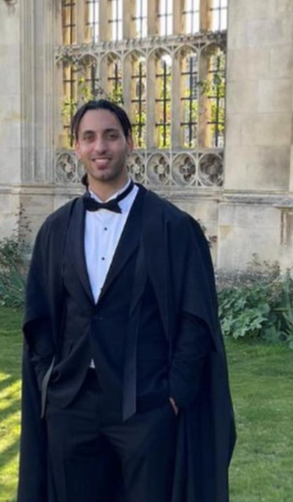 Man wearing a tuxedo and graduation gown. 