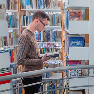 Student looking through books in the Sabhal Mòr Ostaig campus library
