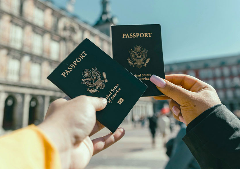 Close-up of the hands of two people which are holding up their passports ready for adventure