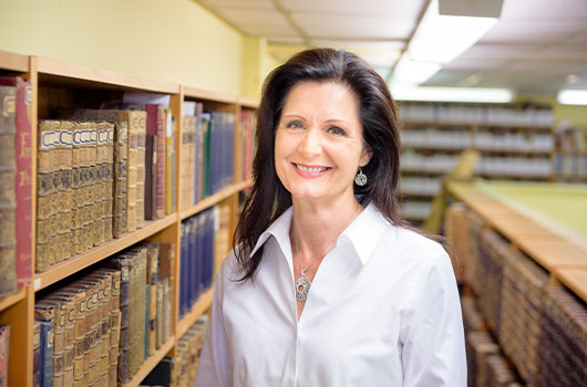 Theresa in a library with volumes of historical books