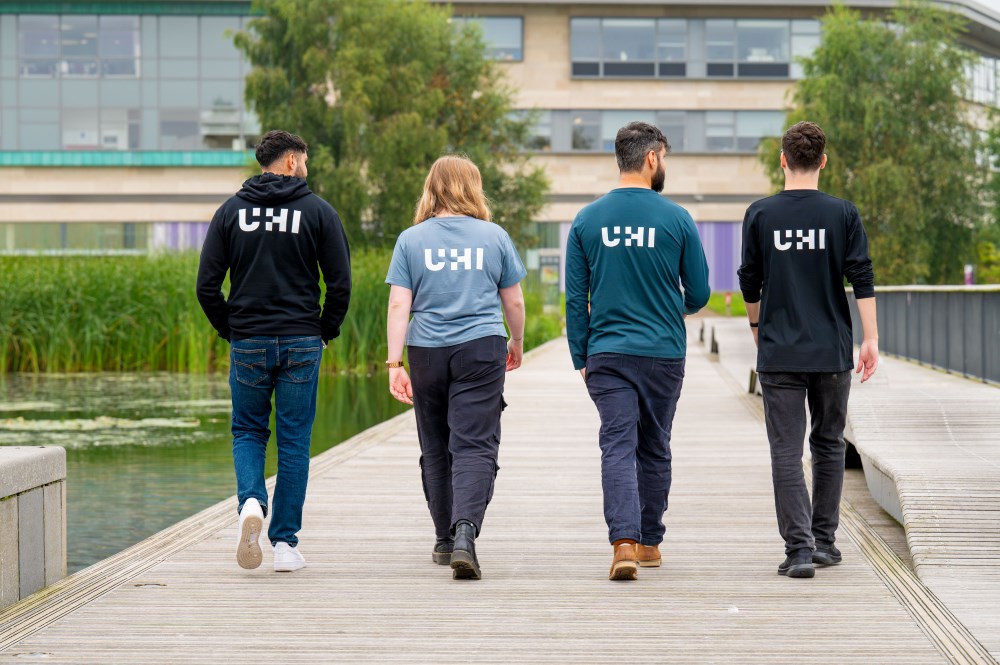 Four people walking away from the camera, each with UHI logo on their back